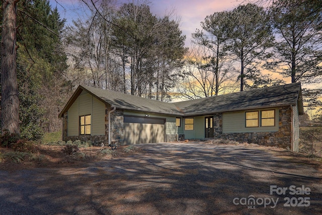 view of front facade featuring a garage, stone siding, and driveway