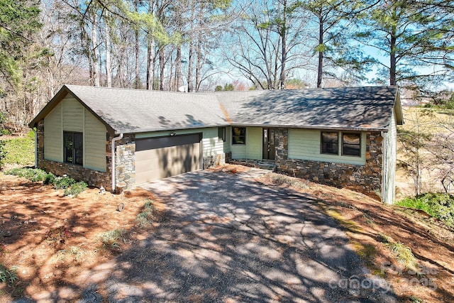 view of front facade with an attached garage, stone siding, aphalt driveway, and roof with shingles