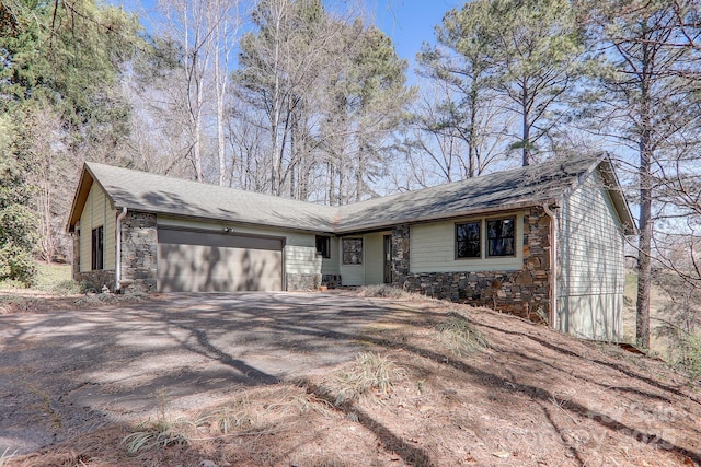 view of front of house with a garage, stone siding, and aphalt driveway