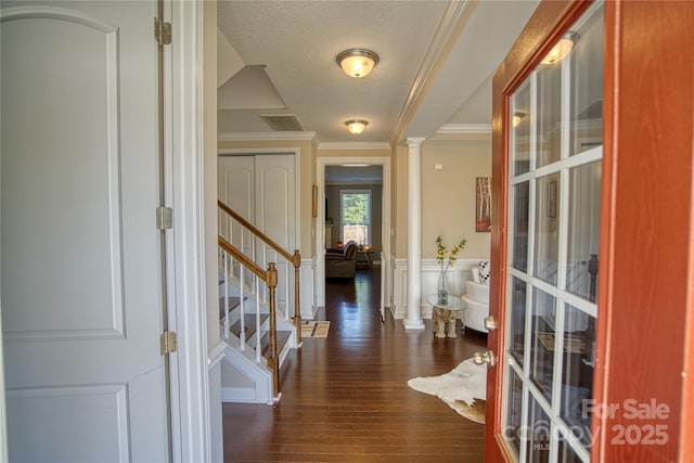 entrance foyer with a textured ceiling, ornate columns, crown molding, and dark hardwood / wood-style floors