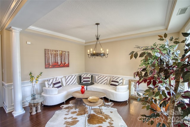 living room featuring a chandelier, dark hardwood / wood-style floors, a tray ceiling, and crown molding