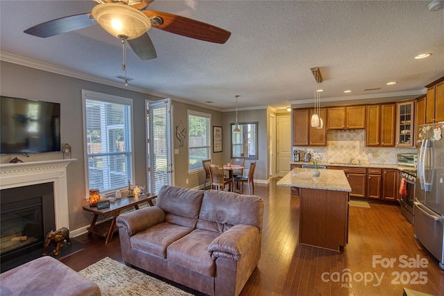 kitchen with a center island, crown molding, light stone countertops, decorative light fixtures, and stainless steel appliances