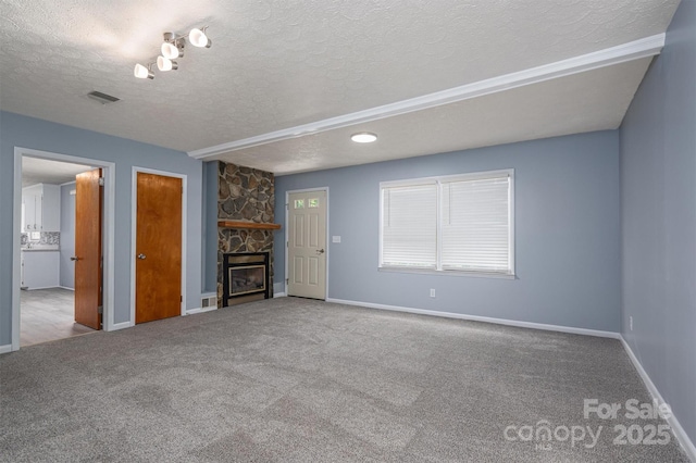 unfurnished living room with a stone fireplace, light colored carpet, and a textured ceiling