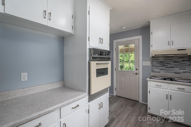 kitchen with white appliances, crown molding, white cabinetry, tasteful backsplash, and light hardwood / wood-style floors