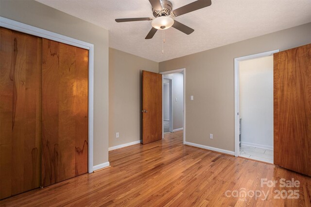 unfurnished bedroom featuring light hardwood / wood-style flooring, a textured ceiling, ceiling fan, and a closet