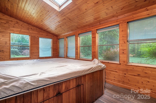 unfurnished bedroom featuring wood ceiling, vaulted ceiling with skylight, and wood walls