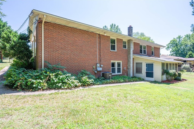 view of front of home with cooling unit and a front lawn