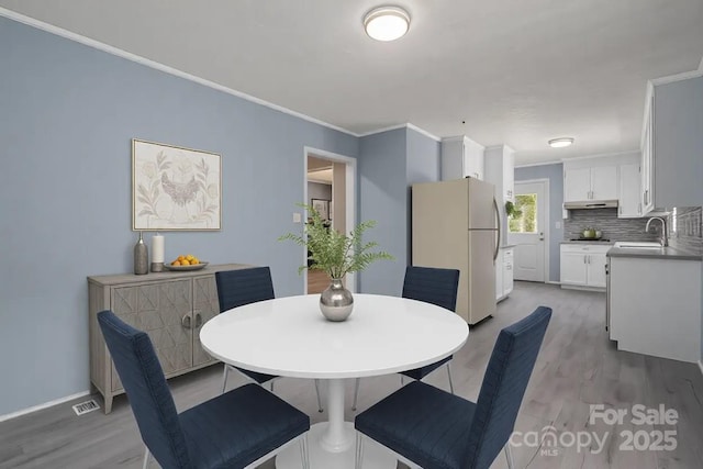 dining space with crown molding, sink, and hardwood / wood-style floors