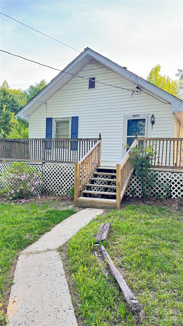 rear view of house with a deck and a lawn