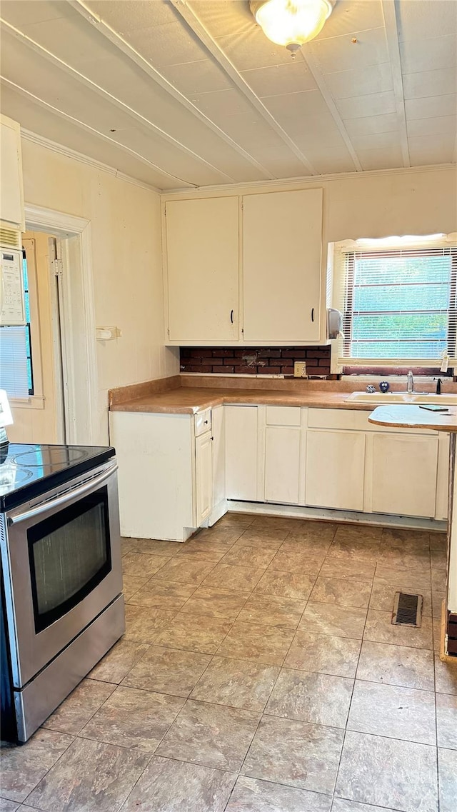 kitchen with white cabinets, light tile floors, and stainless steel electric range