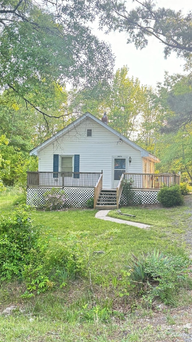 rear view of property with a wooden deck and a lawn