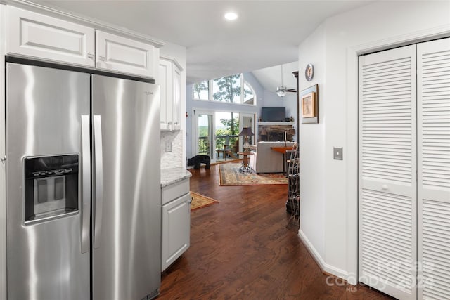 kitchen with white cabinetry, dark wood-type flooring, a stone fireplace, light stone counters, and stainless steel refrigerator with ice dispenser