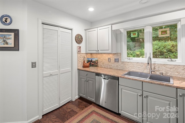 kitchen with backsplash, stainless steel dishwasher, gray cabinetry, sink, and dark hardwood / wood-style floors