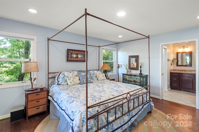 bedroom featuring connected bathroom, hardwood / wood-style flooring, and multiple windows