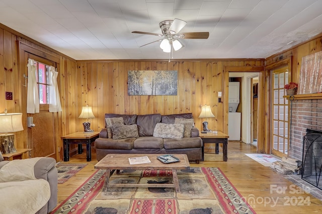 living room featuring ceiling fan, hardwood / wood-style flooring, a fireplace, and wooden walls