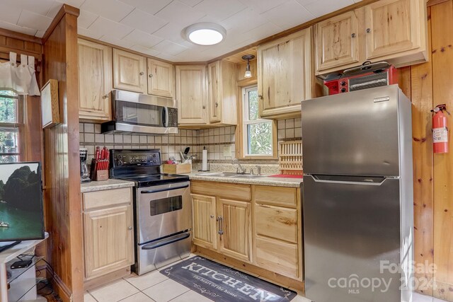 kitchen with sink, a healthy amount of sunlight, appliances with stainless steel finishes, and light tile floors