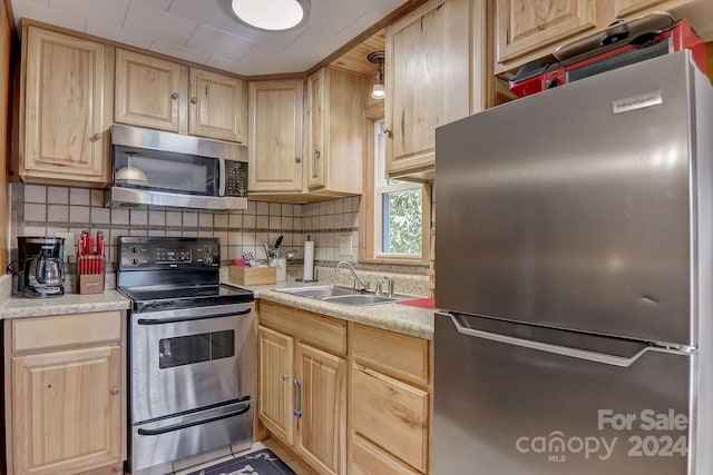 kitchen with light brown cabinetry, tasteful backsplash, stainless steel appliances, and sink