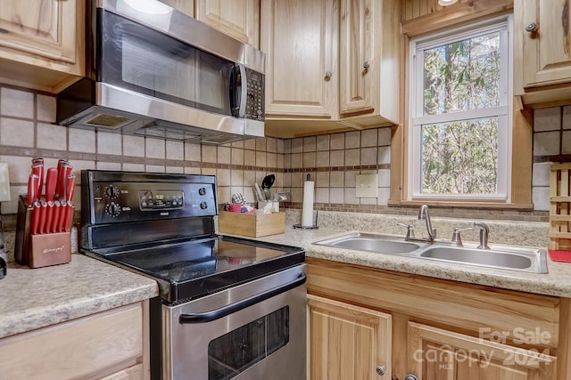 kitchen with light brown cabinets, tasteful backsplash, and stainless steel appliances