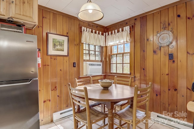 dining area featuring a baseboard radiator, wood walls, and light tile floors