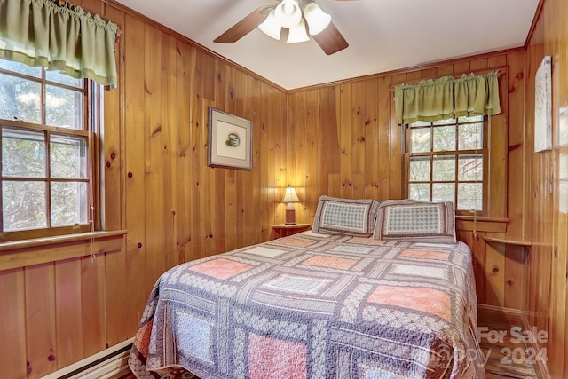 bedroom featuring wooden walls, baseboard heating, ceiling fan, and ornamental molding