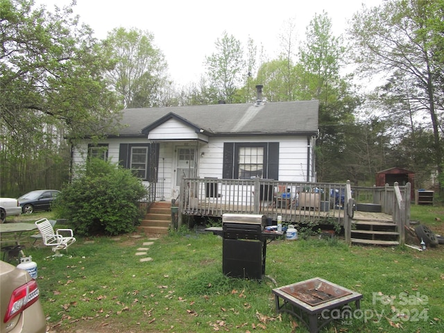 view of front of house with a front yard, an outdoor fire pit, and a wooden deck