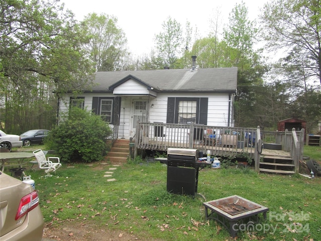 view of front of property with a front lawn, a wooden deck, and a fire pit