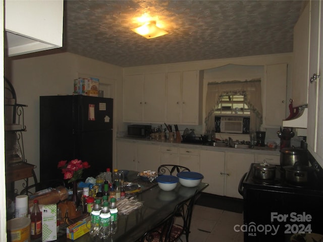 kitchen with white cabinets, black appliances, sink, light tile floors, and an AC wall unit