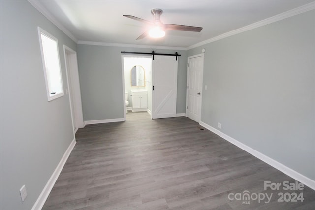 spare room with ceiling fan, crown molding, a barn door, and hardwood / wood-style floors