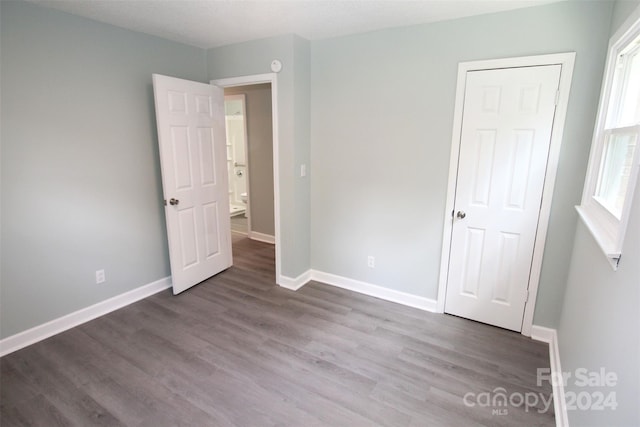 unfurnished bedroom featuring dark wood-type flooring and multiple windows