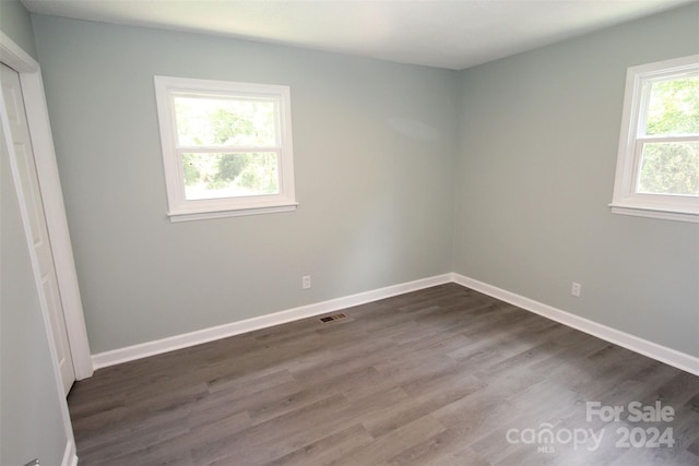 unfurnished room with dark hardwood / wood-style flooring and a healthy amount of sunlight