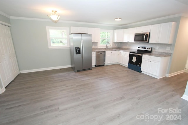 kitchen featuring stainless steel appliances, white cabinetry, and tasteful backsplash