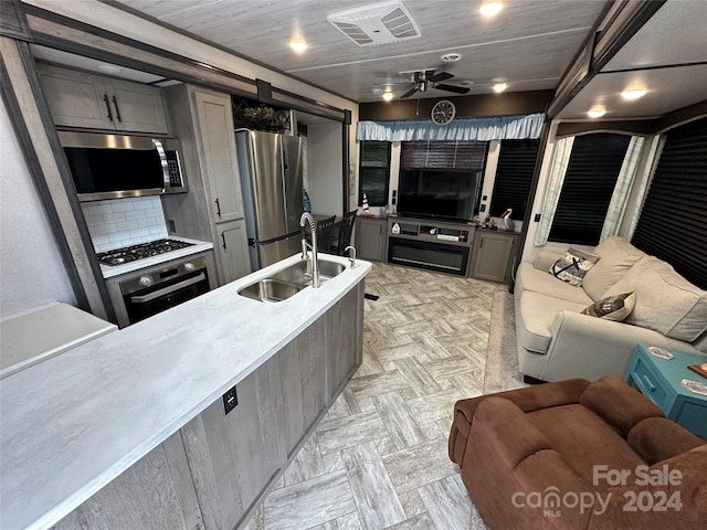 kitchen with appliances with stainless steel finishes, ceiling fan, light parquet flooring, sink, and tasteful backsplash