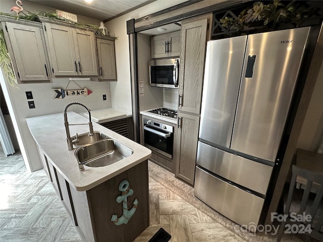 kitchen featuring crown molding, gray cabinets, appliances with stainless steel finishes, sink, and light parquet flooring