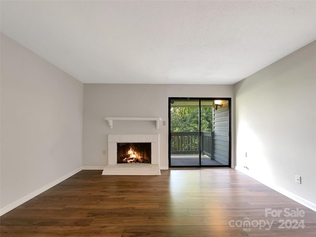 unfurnished living room featuring dark hardwood / wood-style flooring, a textured ceiling, and a fireplace