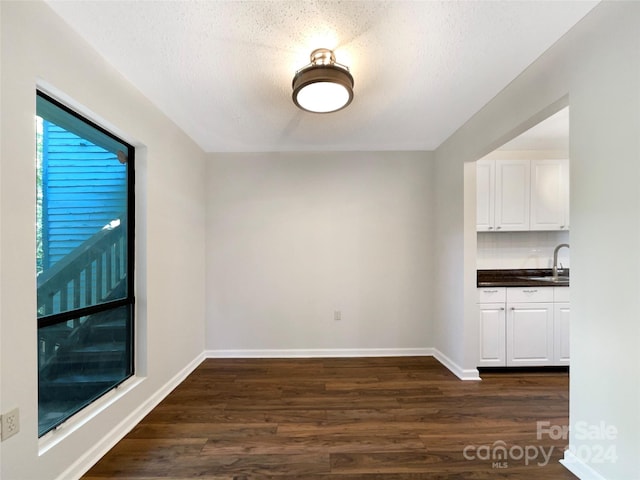 empty room with dark hardwood / wood-style floors, sink, and a textured ceiling