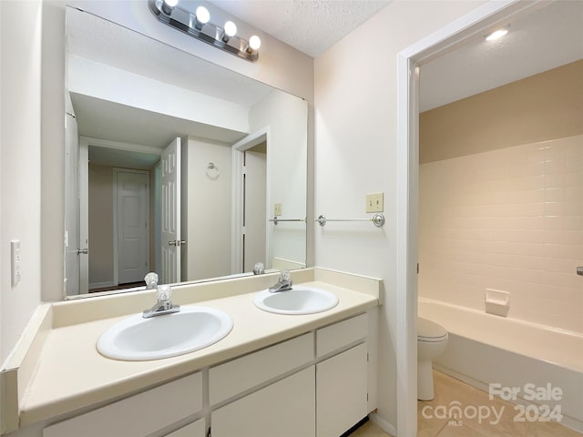 full bathroom featuring shower / bathing tub combination, large vanity, tile flooring, toilet, and a textured ceiling