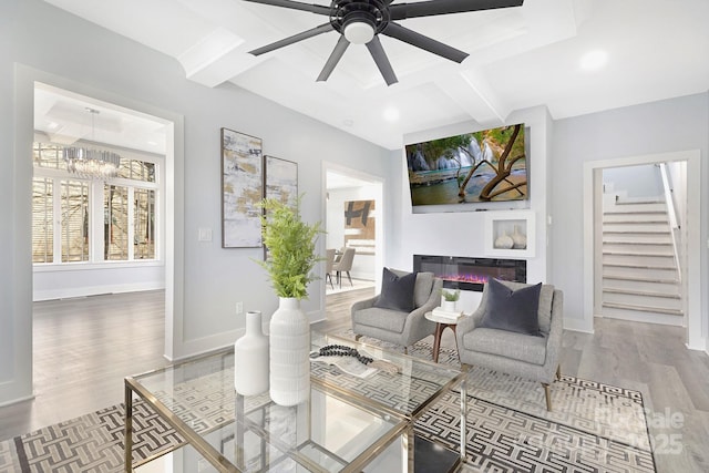 living room with coffered ceiling, hardwood / wood-style floors, beamed ceiling, and ceiling fan with notable chandelier