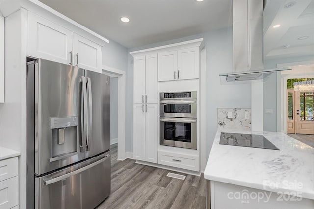 kitchen featuring ventilation hood, light hardwood / wood-style flooring, light stone counters, white cabinetry, and stainless steel appliances