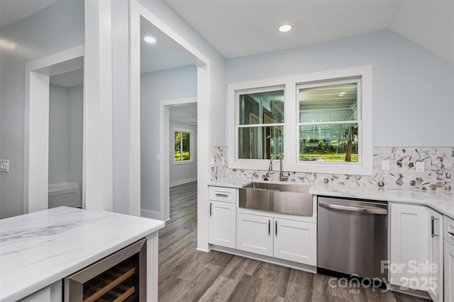 kitchen with light stone counters, stainless steel dishwasher, beverage cooler, sink, and white cabinetry