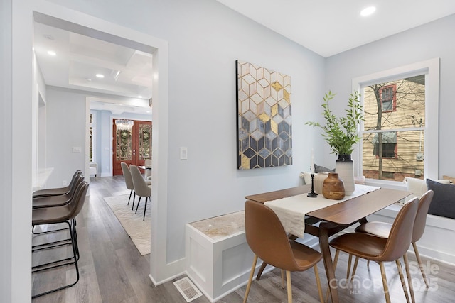 dining area with wood-type flooring, a wealth of natural light, coffered ceiling, and beam ceiling