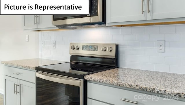 kitchen with tasteful backsplash, light stone countertops, and stainless steel electric range