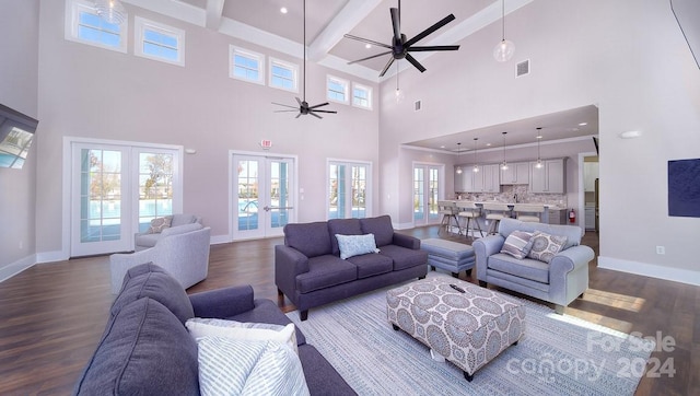 living room featuring ceiling fan, beamed ceiling, french doors, hardwood / wood-style flooring, and a high ceiling