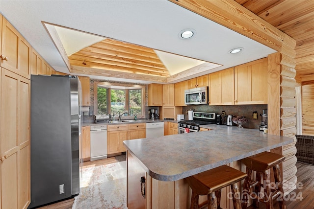 kitchen with appliances with stainless steel finishes, light hardwood / wood-style flooring, a breakfast bar, and light brown cabinets