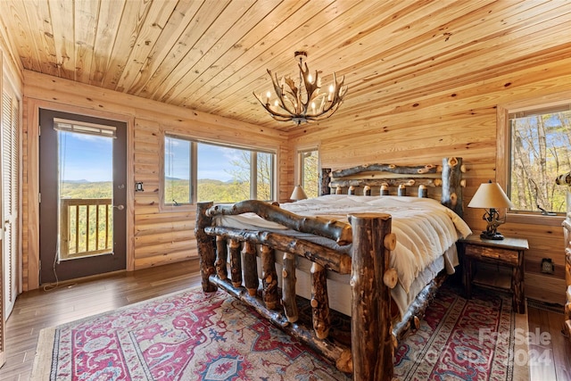 bedroom with access to outside, rustic walls, hardwood / wood-style flooring, wood ceiling, and a chandelier