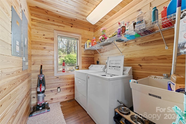 laundry area featuring wooden walls, washer and clothes dryer, sink, wood ceiling, and light hardwood / wood-style floors