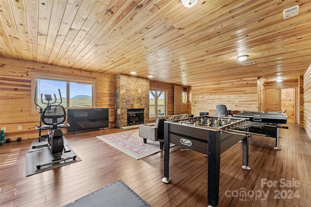 game room with a healthy amount of sunlight, wooden ceiling, hardwood / wood-style flooring, and a stone fireplace