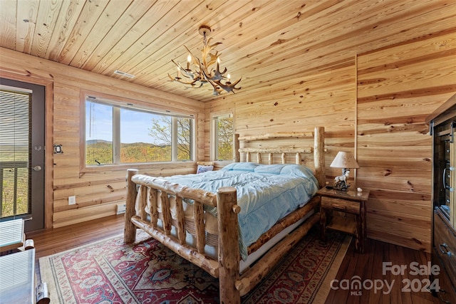 bedroom with an inviting chandelier, wood-type flooring, log walls, and multiple windows