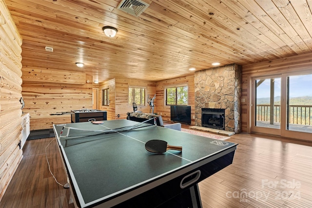 recreation room with dark hardwood / wood-style flooring, wood walls, a fireplace, and wooden ceiling