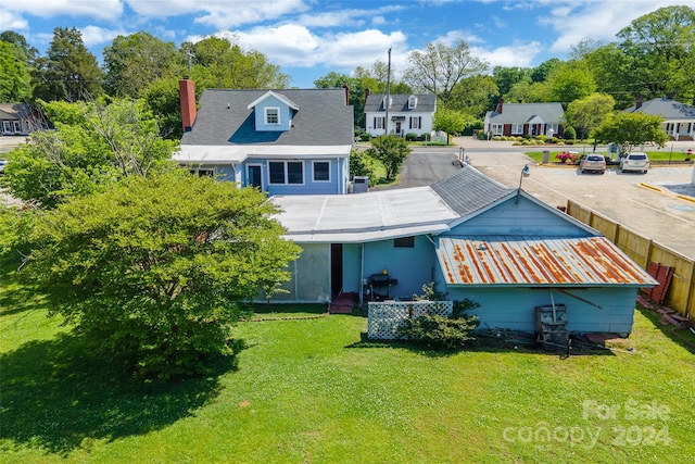 back of house with central AC unit and a lawn