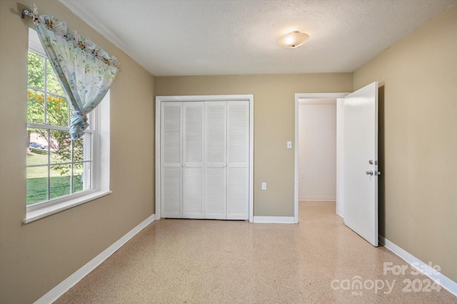 unfurnished bedroom featuring a closet, a textured ceiling, and multiple windows